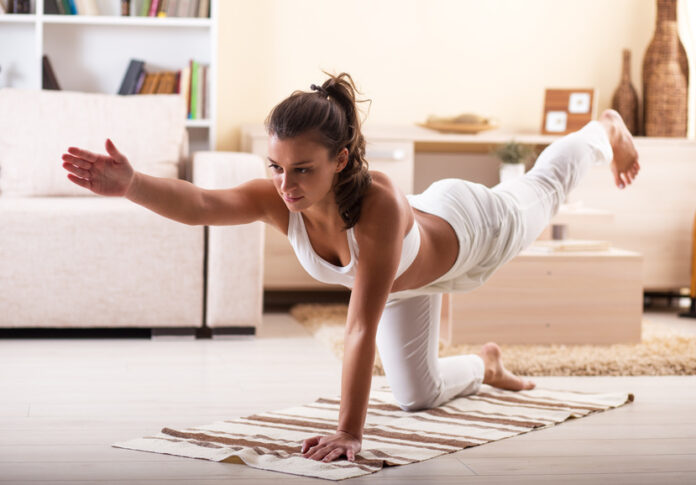 Frau macht Yoga, Dehnübung, Sport zuhause