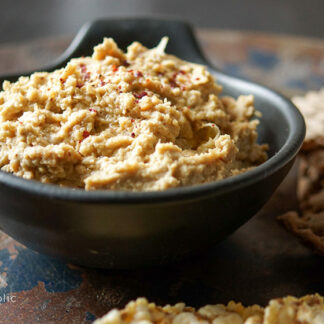 Hummus mit Sumach, Tahini, Zitronensaft, Cayenne-Pfeffer, Kichererbsen in schwarzer Schüssel