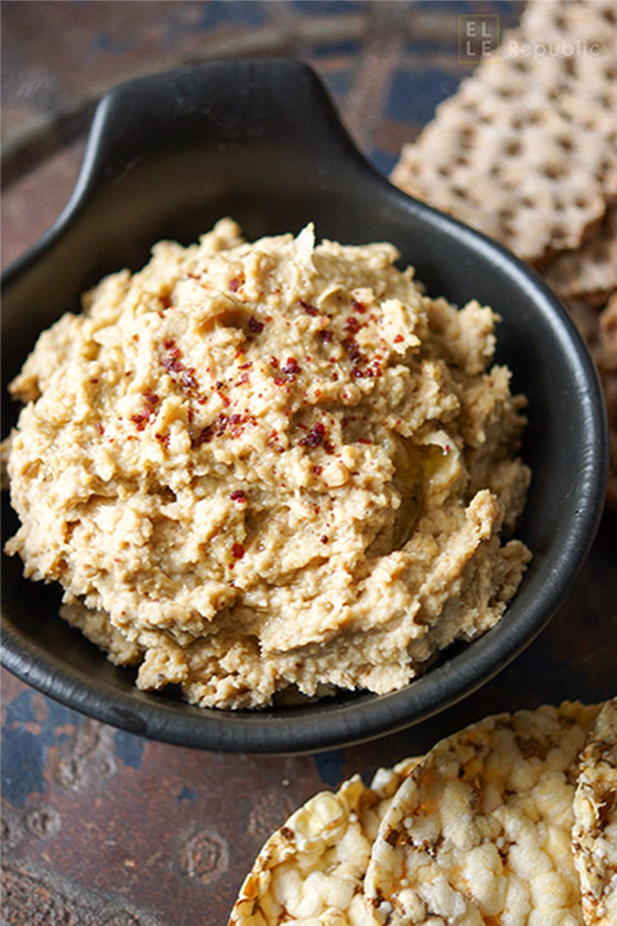 Hummus mit Sumach, Tahini, Zitronensaft, Cayenne-Pfeffer, Kichererbsen in schwarzer Schüssel