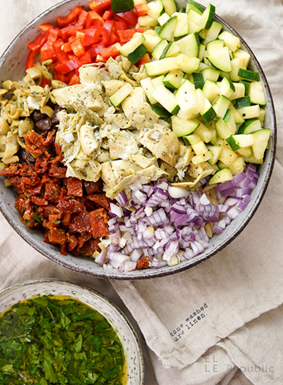 Mediterranean orzo pasta salad recipe with artichokes, pointed red pepper, zucchini, olives, sun-dried tomatoes and feta cheese.
