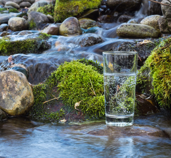 Warum Wasser trinken wichtig ist, Glas Wasser in Fluss