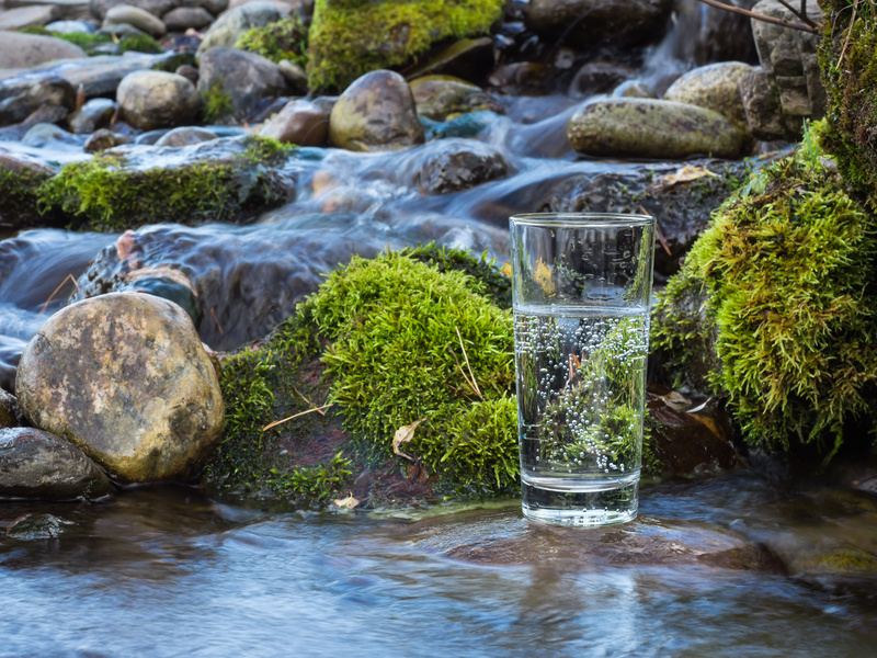 Warum Wasser trinken wichtig ist, Glas Wasser in Fluss