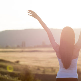 Tipps gegen Nachmittagsmüdigkeit: Frau bei Sonnenaufgang in Natur
