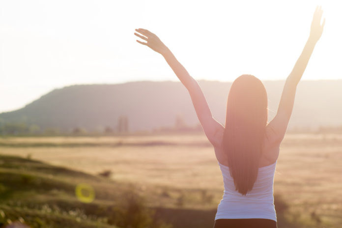 Tipps gegen Nachmittagsmüdigkeit: Frau bei Sonnenaufgang in Natur