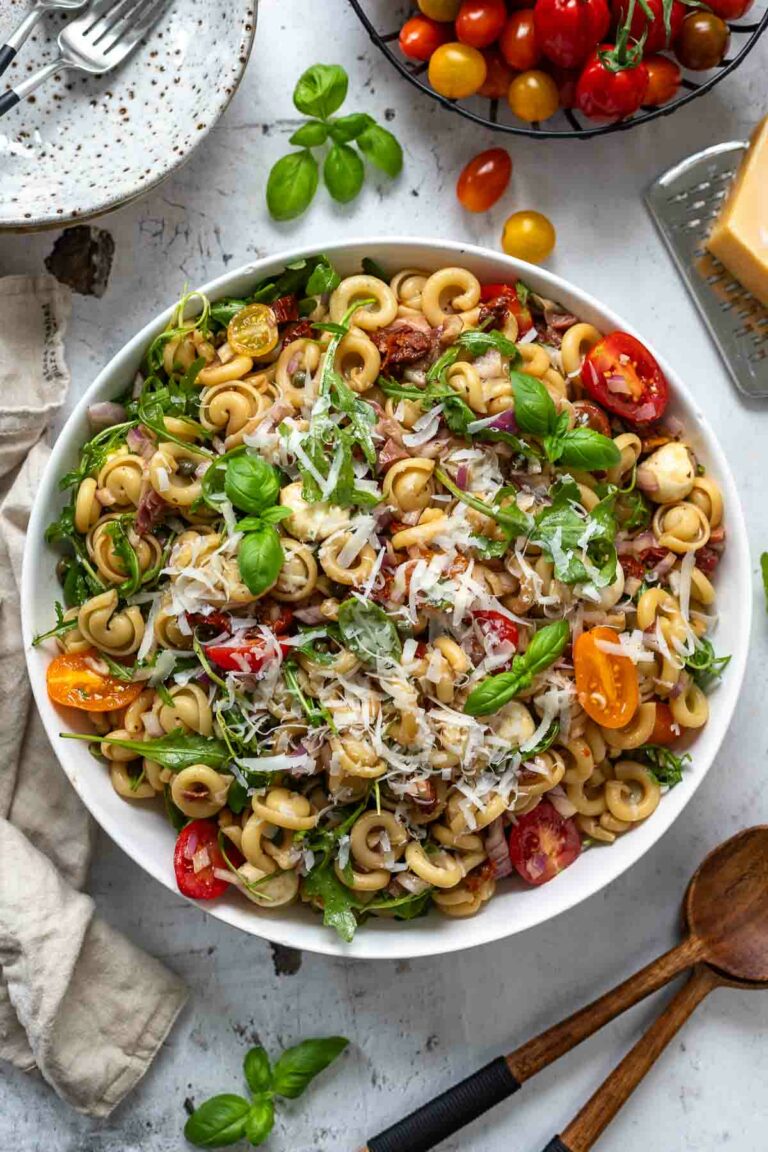 Gesunder Pasta Rezept mit Tomaten, süße, rote Zwiebeln, Basilikum, Rucola, sonnengetrocknete Tomaten, Kapern und Parmaschinken mit Balsamico-Olivenöl-Dressing.