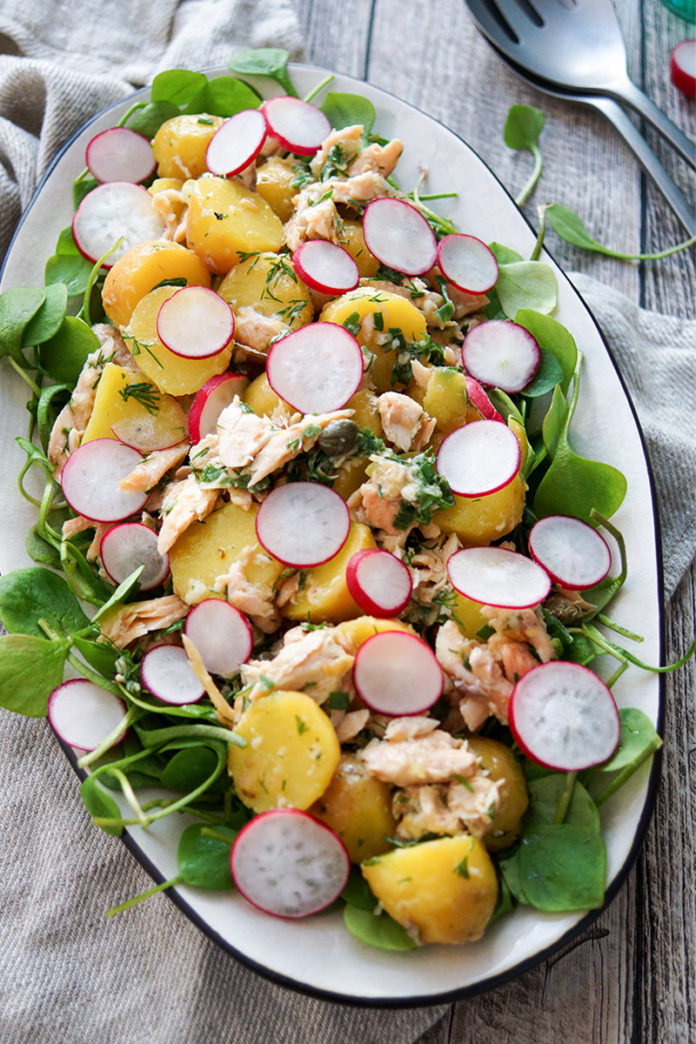 Kartoffelsalat mit Räuchersaibling Rezept. Jungen Kartoffeln, frischem Postelein (Portulak), Kapern, Frühlingszwiebel und Radieschen, mit einem Dressing aus Zitronensaft, Meerrettich, Dill und Olivenöl