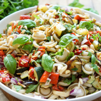 Gesunder Sommer Nudelsalat mit geröstetem Gemüse (Paprika, Zucchini, Aubergine und Cherry-Tomaten), getrocknete Tomaten, geröstete Mandelsplitter und frische Kräuter. Vegan