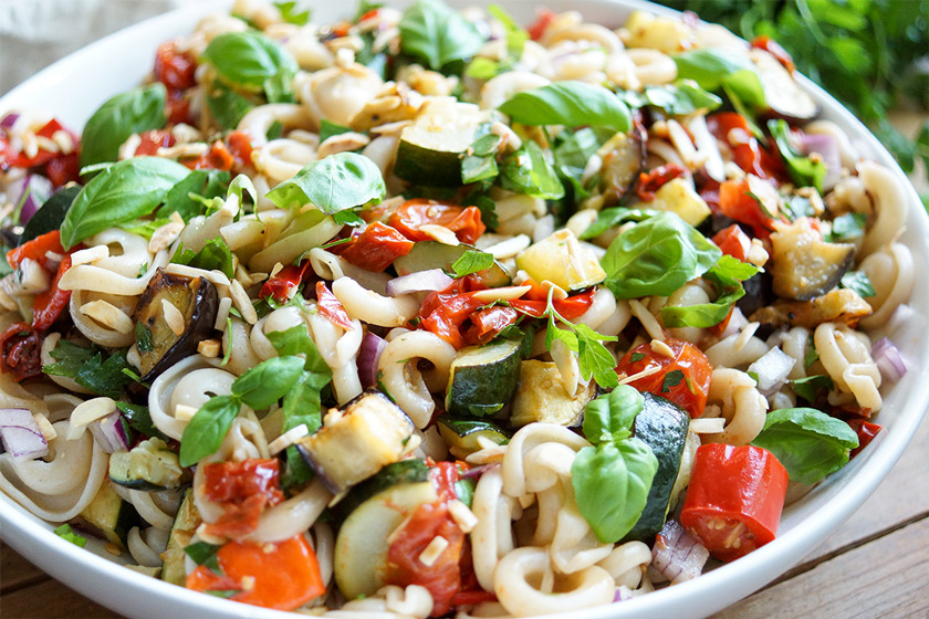 Gesunde Sommer Nudelsalat mit geröstetem Gemüse (Paprika, Zucchini, Aubergine und Cherry-Tomaten), getrocknete Tomaten, geröstete Mandelsplitter und frische Kräuter. Vegan