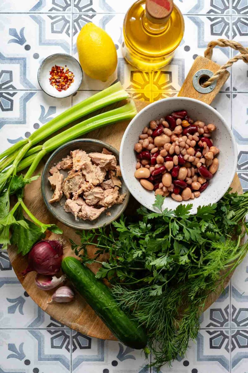 Ingredients for Mediterranean bean salad with tuna, lemon, garlic, herbs, cucumber and celery.