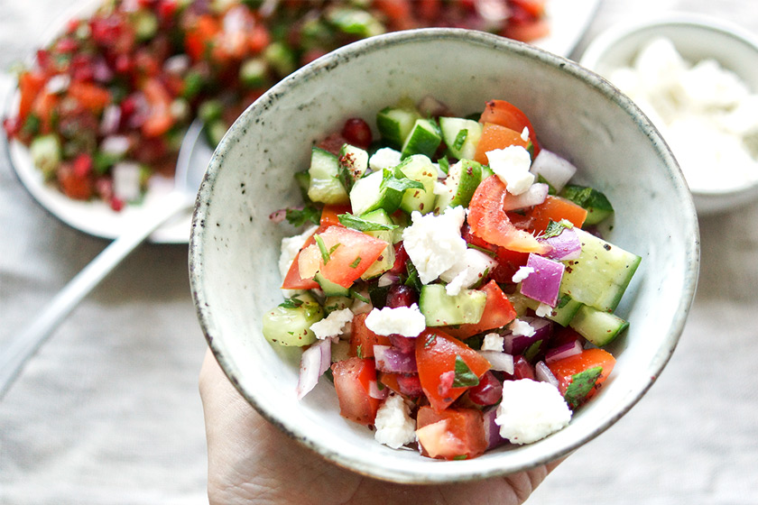 Holding a bowl of Persian Cucumber and Tomato Salad with Pomegranate