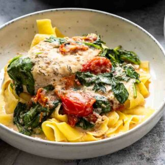 Hähnchenpfanne mit Kokosmilch, Tomaten und Spinat serviert mit Nudeln