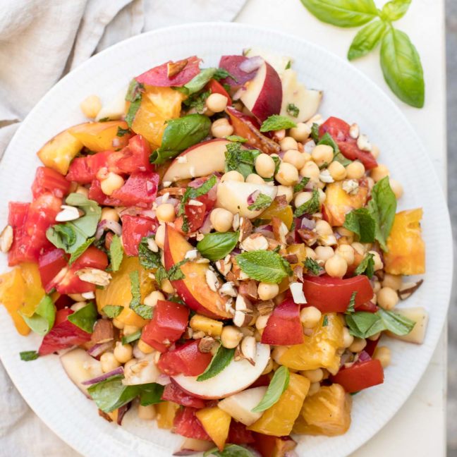 Nektarinensalat mit Tomaten alte Sorte, Kichererbsen, roter Zwiebel, gerösteten Mandeln, Basilikum und Minze. Vegan