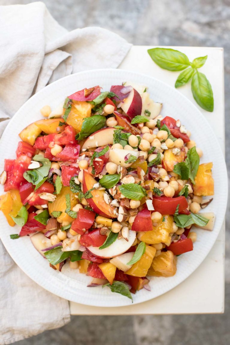 Nektarinensalat mit Tomaten alte Sorte, Kichererbsen, roter Zwiebel, gerösteten Mandeln, Basilikum und Minze. Vegan