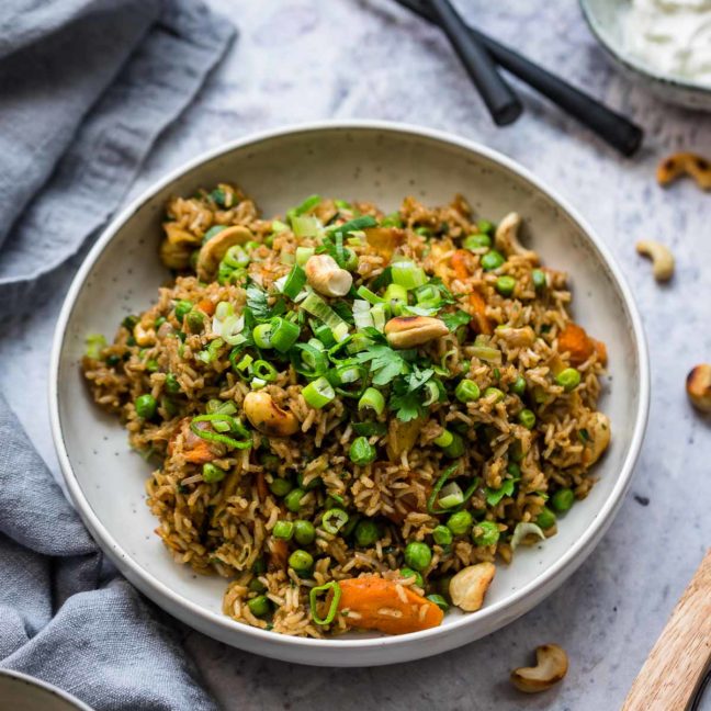 Curry Reis Rezept mit Gemüse – Farbiger Curry-Reis mit knackigem Gemüse, garniert mit frischen Kräutern und Kashewkerne.