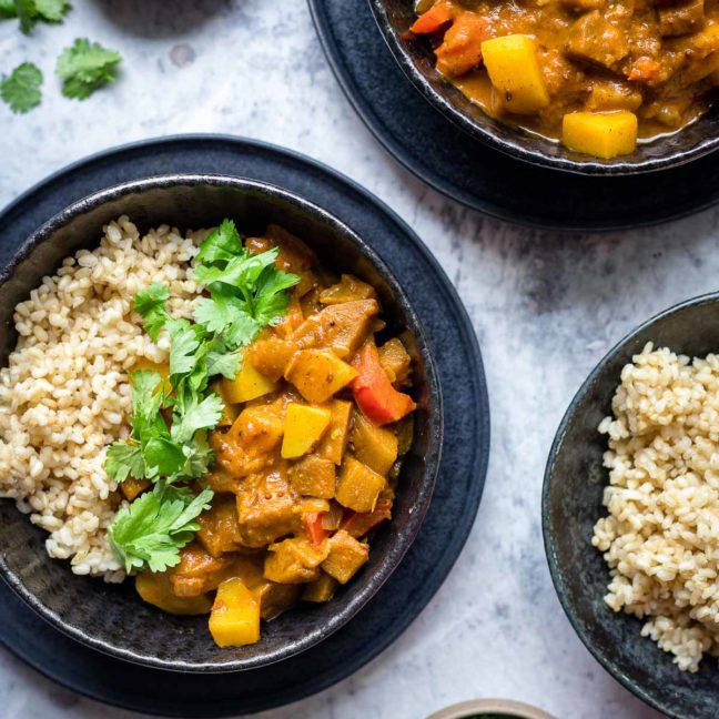 Indisches Auberginen Kartoffel Curry mit Tomaten und Kokosmilch Rezept, serviert mit Vollkornreis, Koriander und Limetten