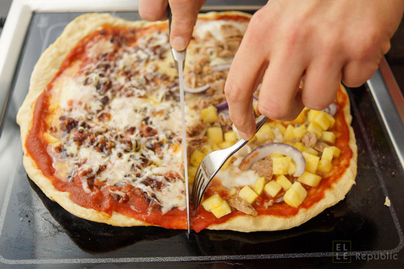 Selbstgemachte Grill-Pizza auf dem Tischgrill schneiden