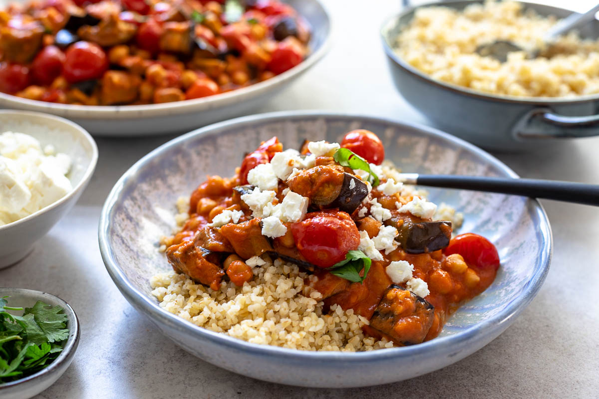Eggplant and tomato stew with chickpeas, tomato and harissa spice served with bulgur and feta cheese