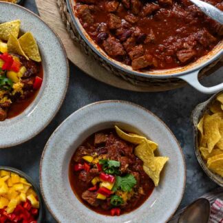 Chili con Carne mit Rindfleisch Rezept serviert mit Paprika, Cheddar-Käse und Tortilla Chips