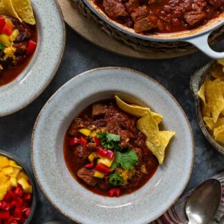 Chili con Carne mit Rindfleisch Rezept serviert mit Paprika, Cheddar-Käse und Tortilla Chips