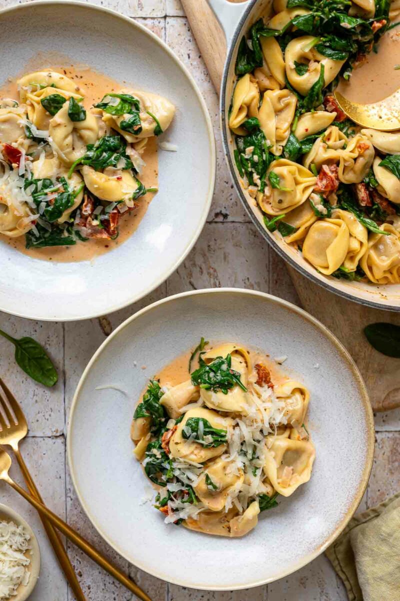 one-pot tortellini skillet with cream sauce, sun-dried tomatoes and spinach served in bowls