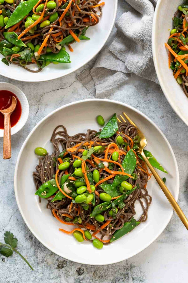 Miso Soba Noodle Salad recipe with sugar snap peas, edamame, julienned carrots, green onion and miso dressing served into bowls
